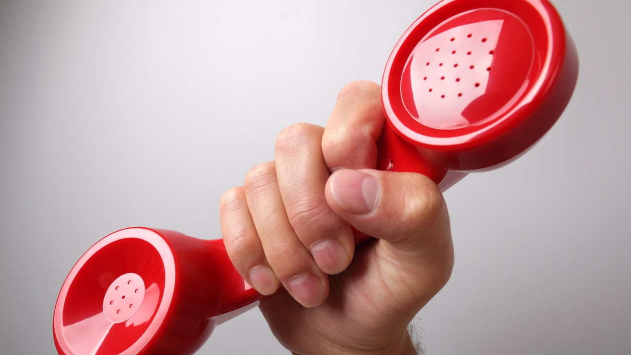 A hand holding a red telephone receiver A hand holding a red telephone receiver