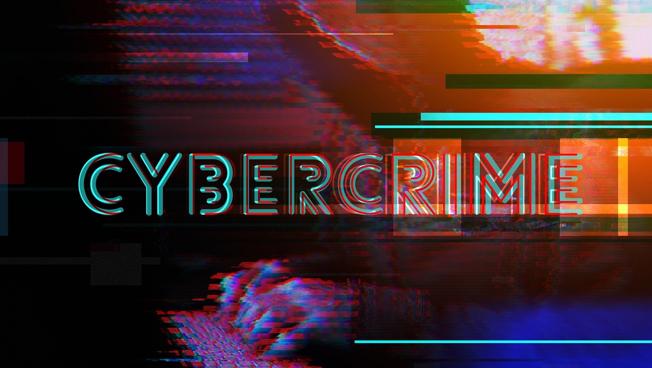 The word CYBERCRIME over image of hands on a laptop keyboard The word CYBERCRIME over image of hands on a laptop keyboard