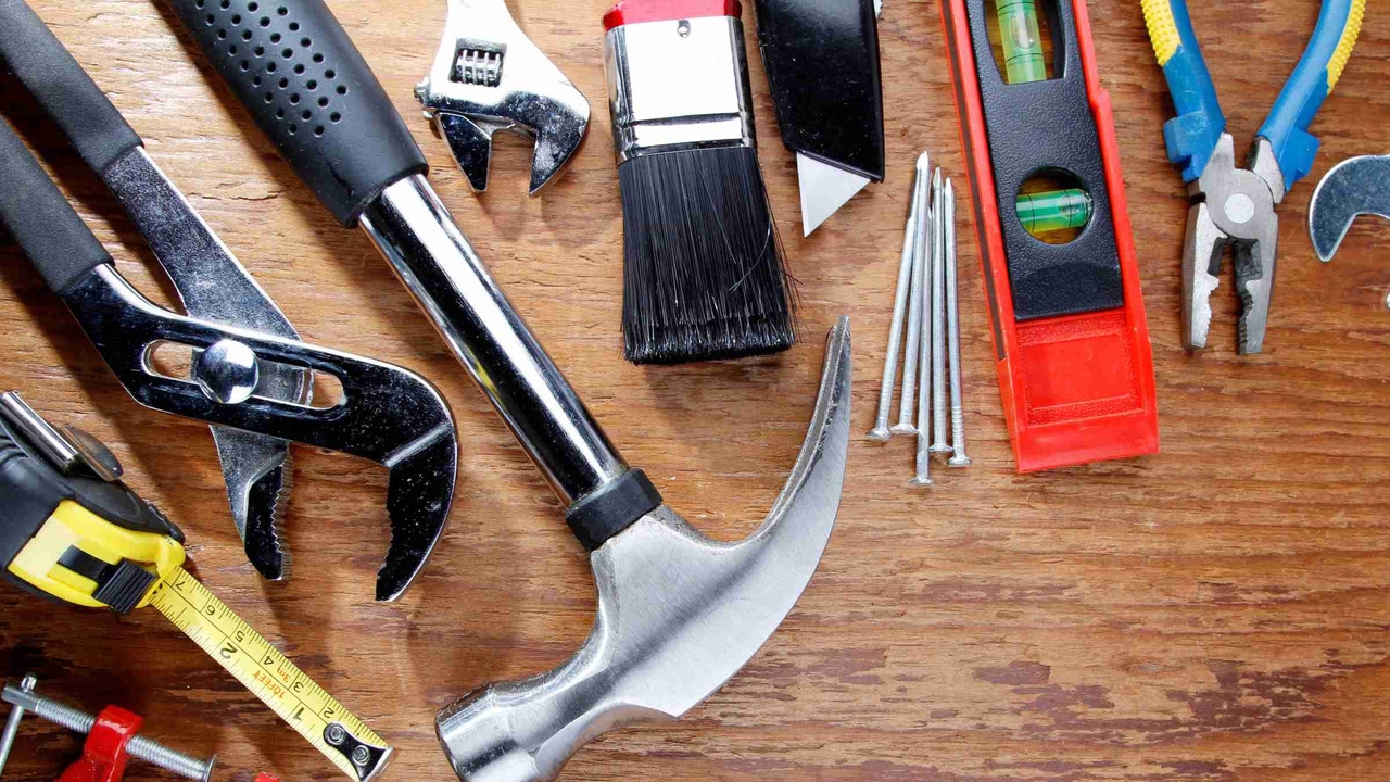 Row of  tools on a table such as screwdrivers, wrenches, and a hammer
